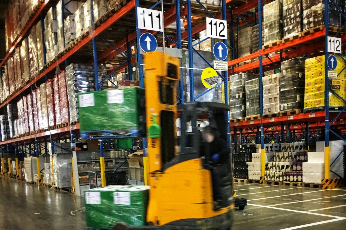 Forklift moving through a warehouse with loaded pallets